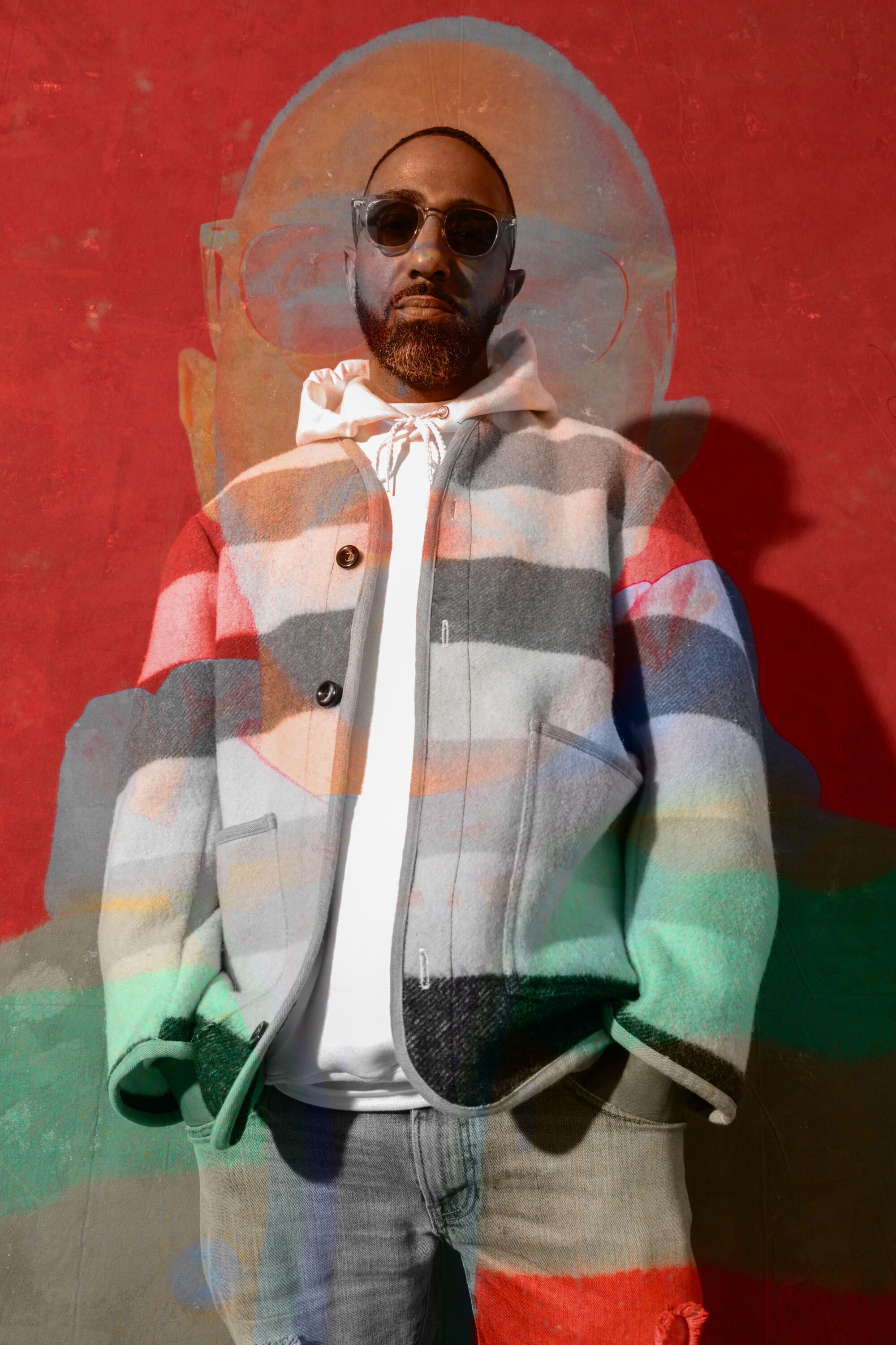 Khalil Kinsey poses in sunglasses, a mural behind him.