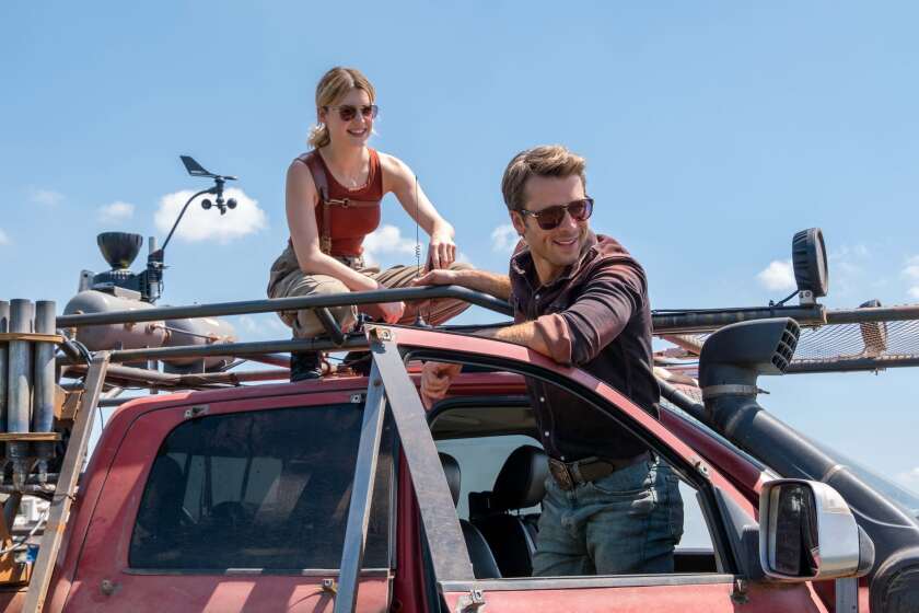 A woman on top of a truck and a man in shades prepare to chase the storm.