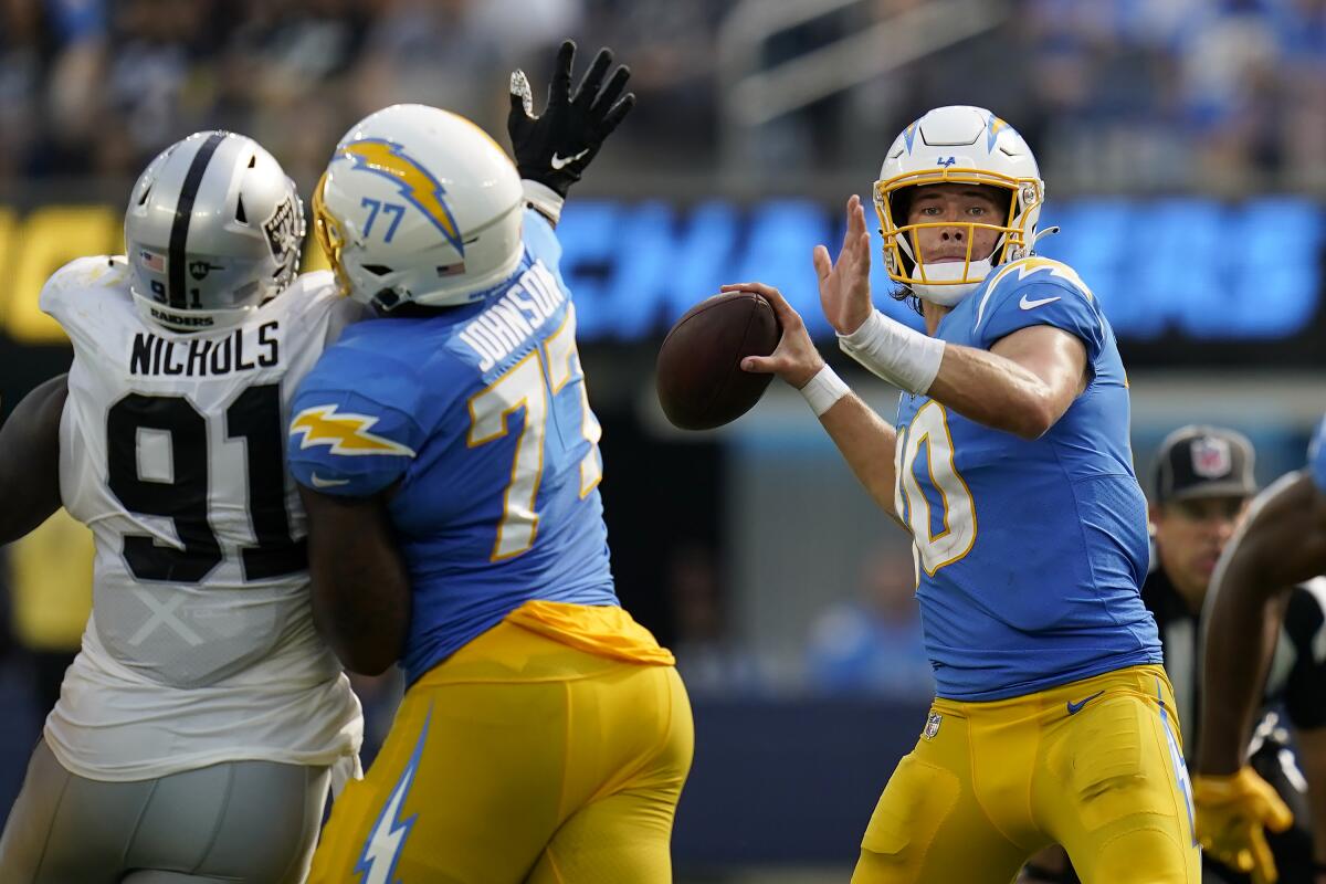 Los Angeles Chargers quarterback Justin Herbert, right, passes as Las Vegas Raiders defensive tackle Bilal Nichols (91) applies pressure during the second half of an NFL football game in Inglewood, Calif., Sunday, Sept. 11, 2022. (AP Photo/Gregory Bull)