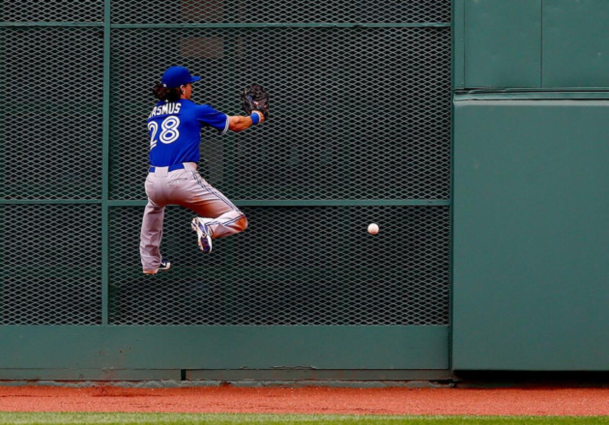 Toronto Blue Jays center fielder Colby Rasmus misses a fly ball in center field before running into the fence.