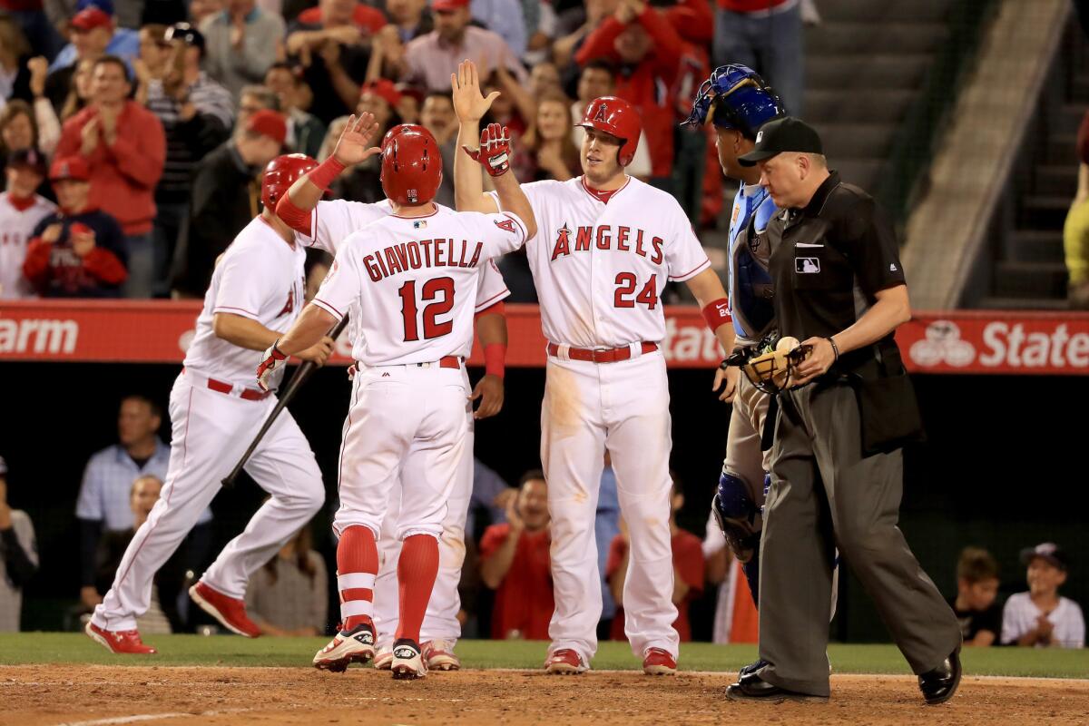 Johnny Giavotella (12) is met by C.J. Cron (24), and Carlos Perez (58) after hitting a three-run home run against the Royals during the fifth inning of a game on April 26.