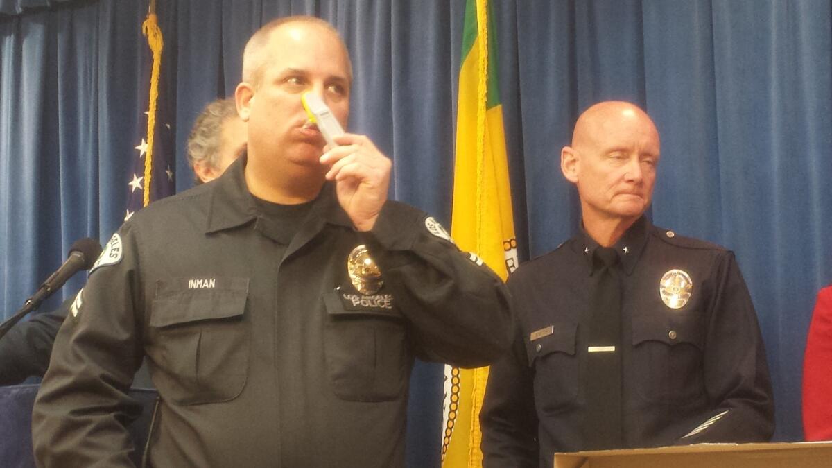 Los Angeles Police Department Officer Don Inman rubs a swab around the inside of his mouth to demonstrate an on-the-spot drug test being used by law enforcement to deter people from driving under the influence of drugs.