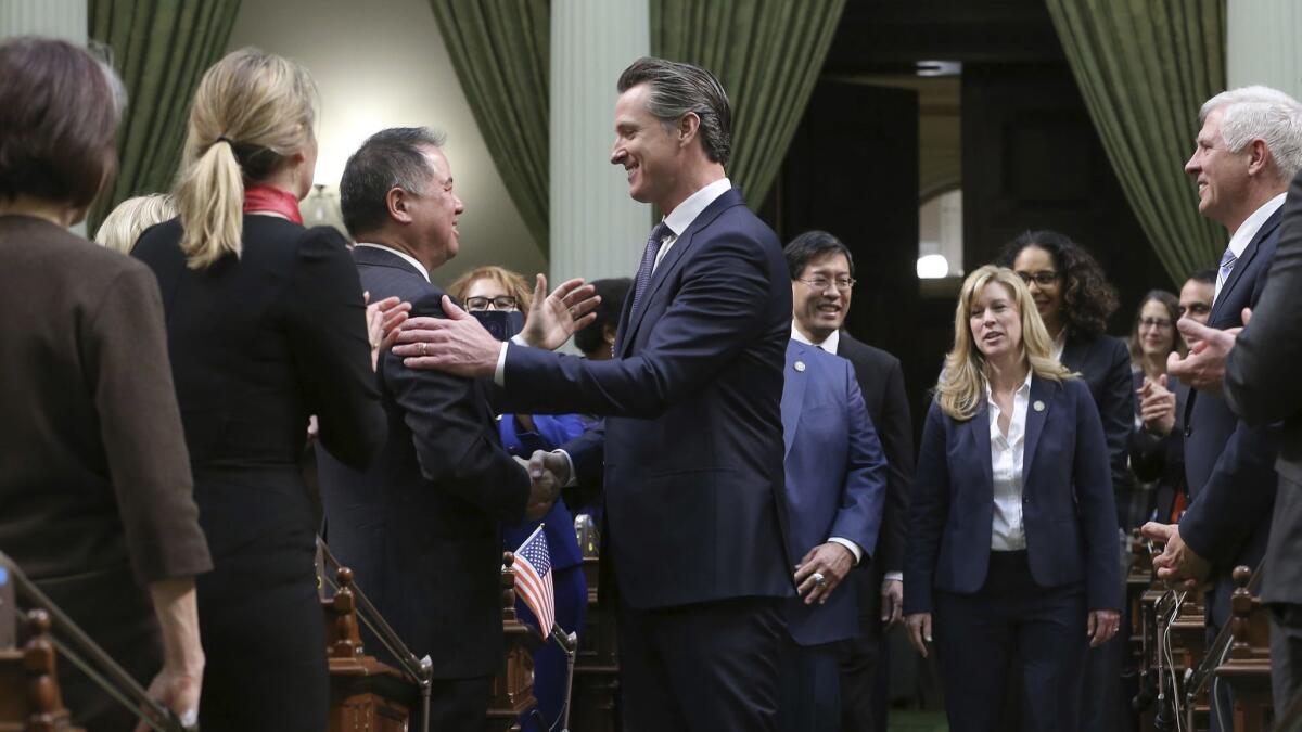 Gov. Gavin Newsom shakes hands with Assemblyman Phil Ting ( D-San Francisco), left, as he enters the Assembly Chambers to deliver his first State of the State address on Feb. 12.