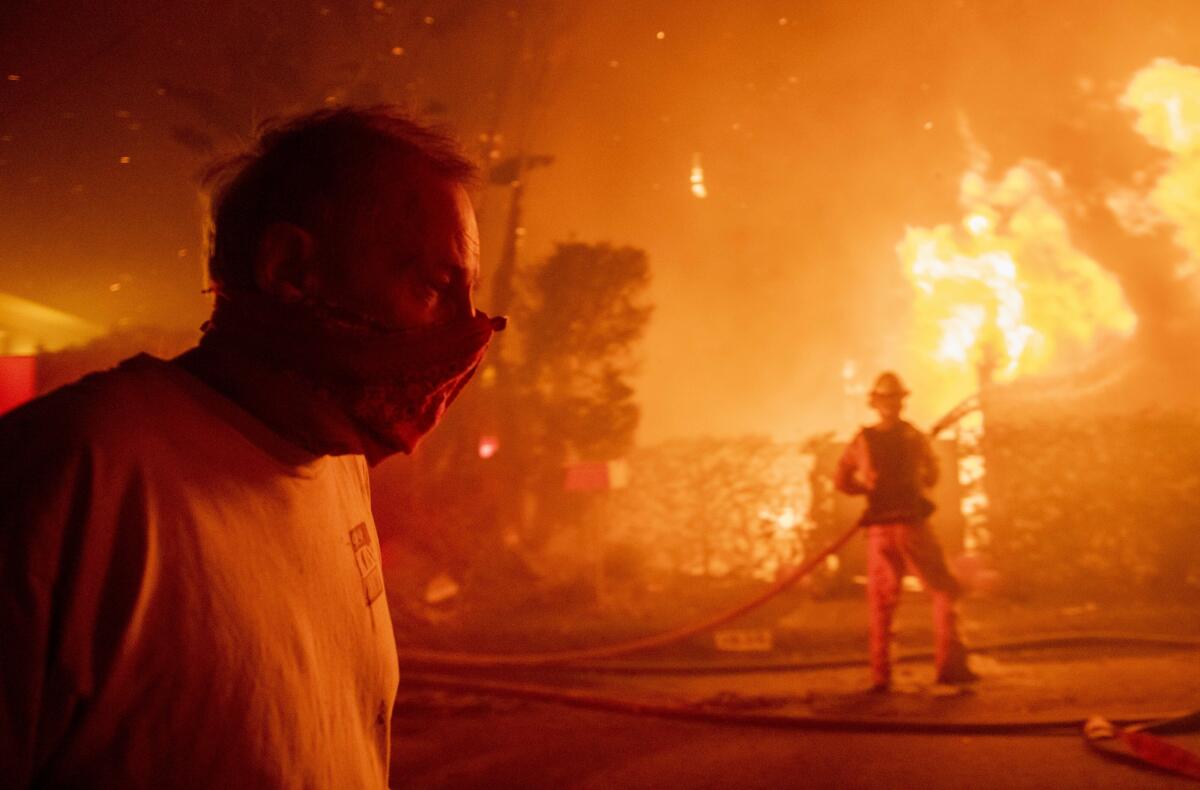 A man walks past a burning home during the Getty fire in Los Angeles on Monday.
