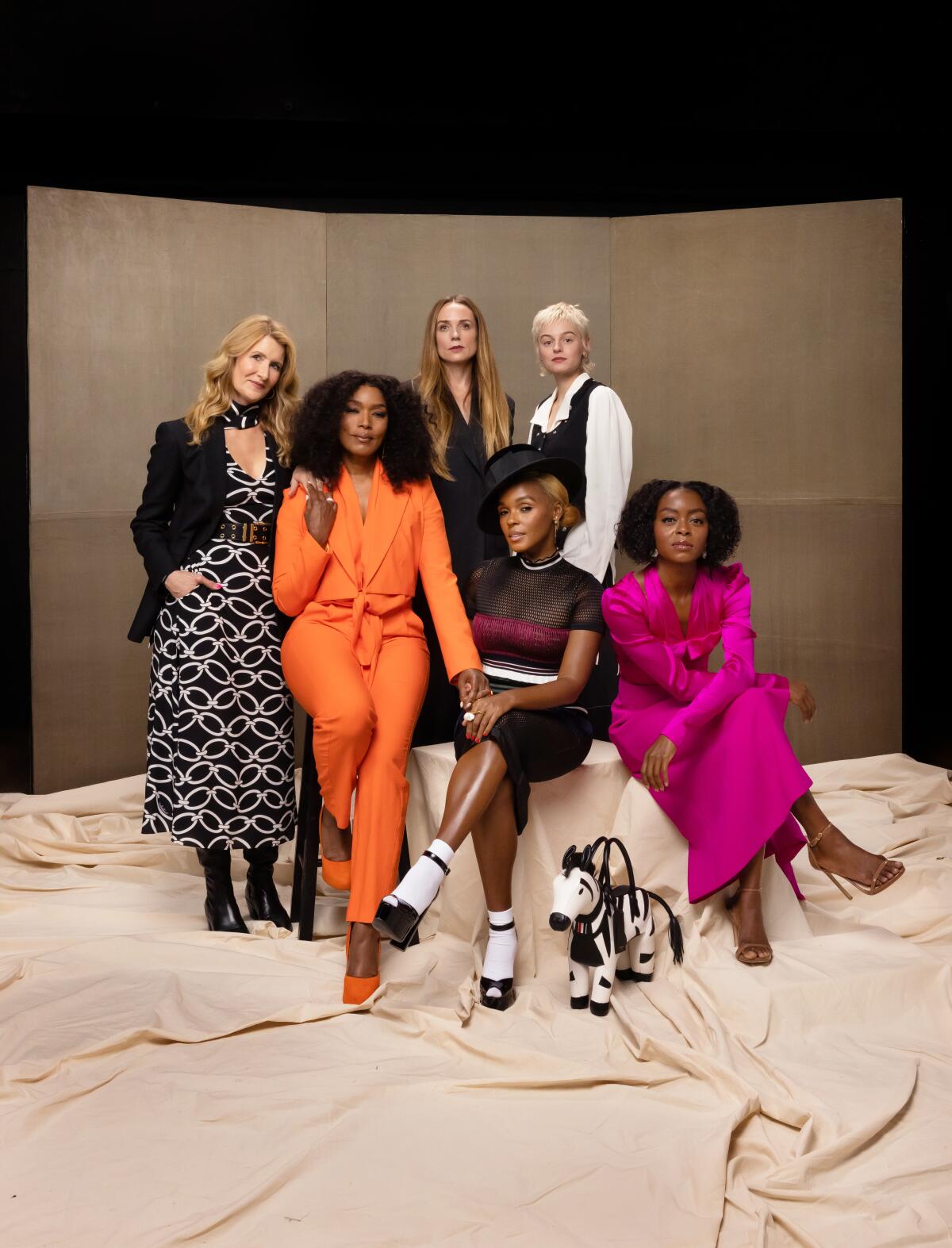 Colorfully dressed women pose on a photo background with a little zebra purse front and center