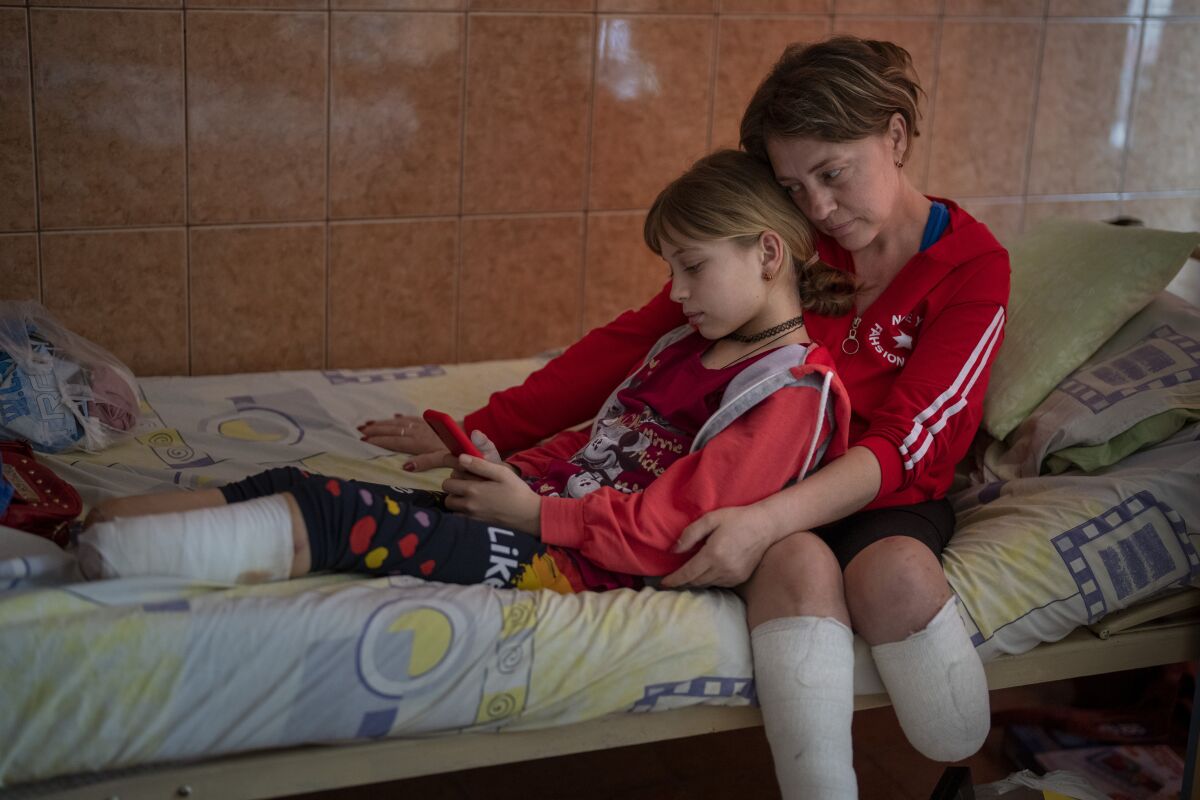 Woman and her daughter sitting on a hospital bed