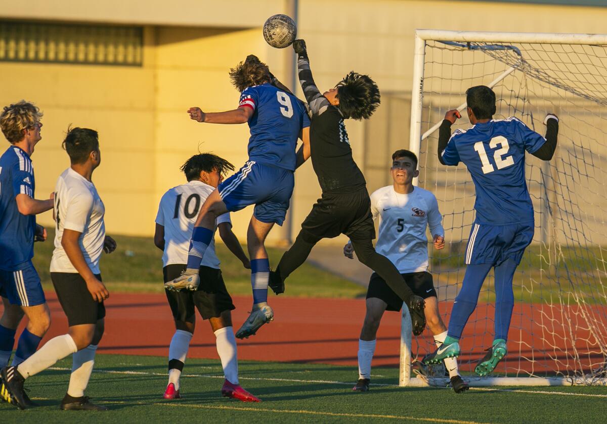 Los Amigos' goalkeeper Jorge Sanchez punches a ball away from Fountain Valley's Devin La Clair during a boys' soccer match.