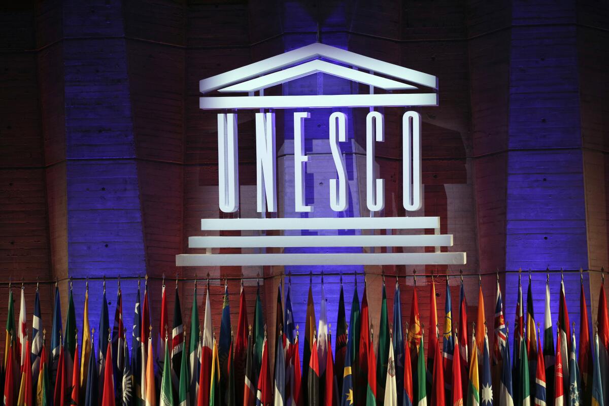 The logo of the United Nations Educational, Scientific and Cultural Organization (UNESCO) is seen above a bunch of flags