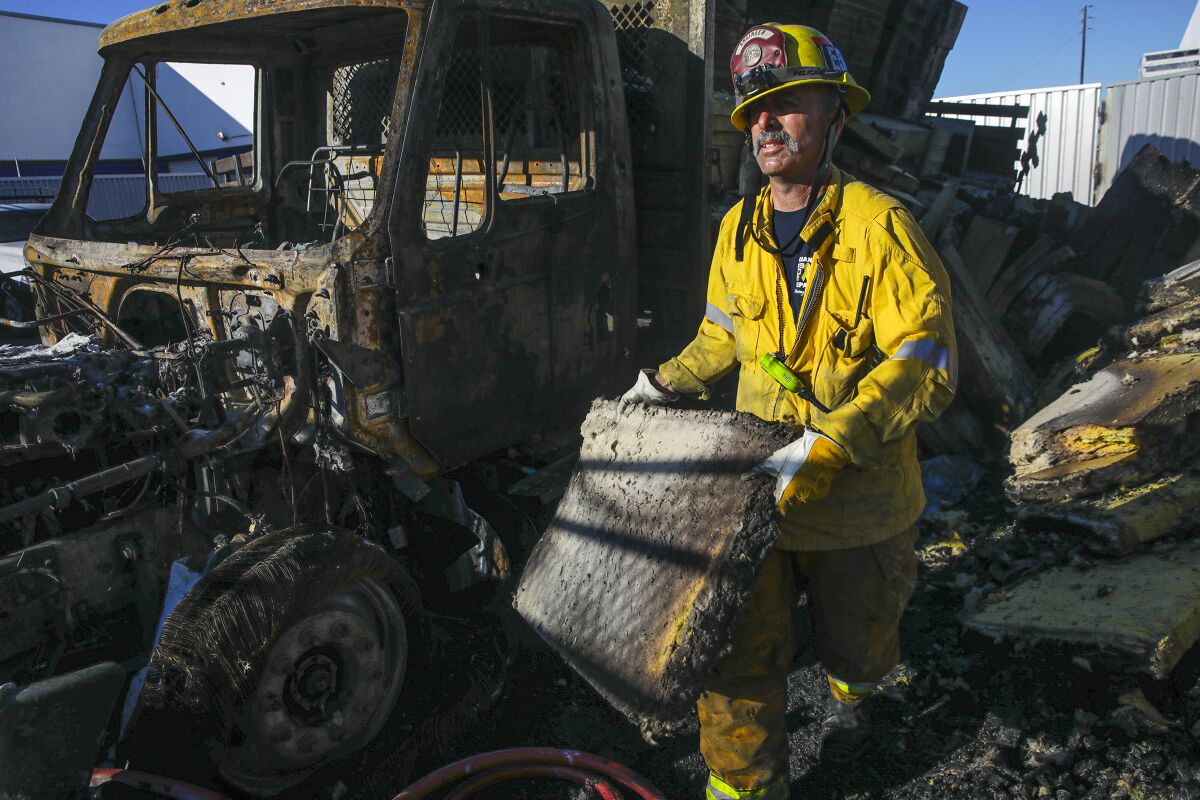 Orange City Fire engineer Norm Glastetter mops up remnants of a four-alarm fire that destroyed a foam manufacturing company