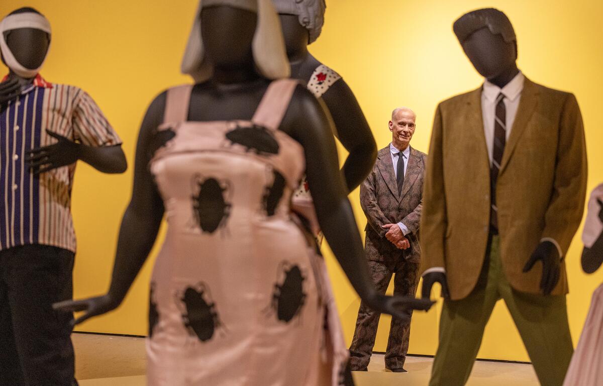 A smiling man stands behind mannequins.