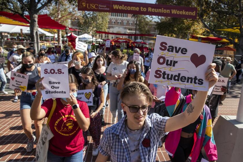LOS ANGELES, CA - October 29 2021: USC freshman Blake Walters, 18, right, marches out in front of a group of USC faculty, students and area residents as they chant slogans and carry signs during a demonstration on the USC campus on Friday, Oct. 29, 2021 in Los Angeles, CA. The demonstration comes one week after sexual misconduct allegations against Sigma Nu fraternity members surfaced. (Brian van der Brug / Los Angeles Times)