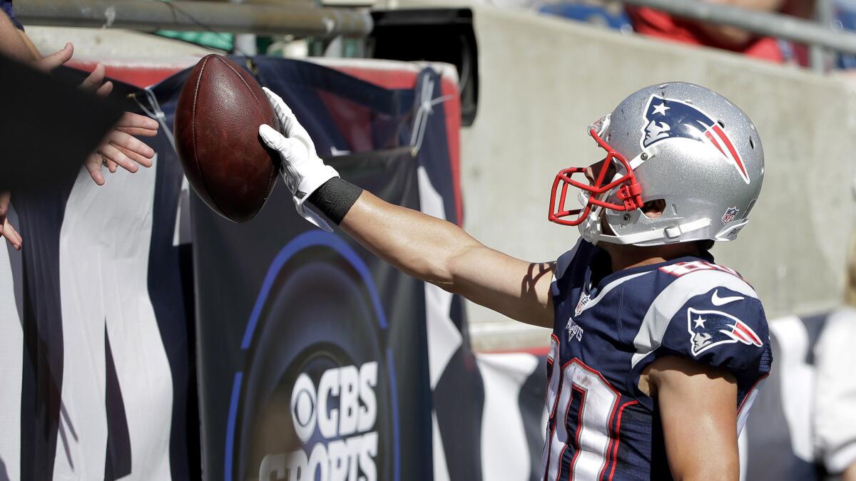 Patriots wide receiver Danny Amendola hands the ball Tom Brady threw for his 400th career touchdown to a fan in the stands Sunday.