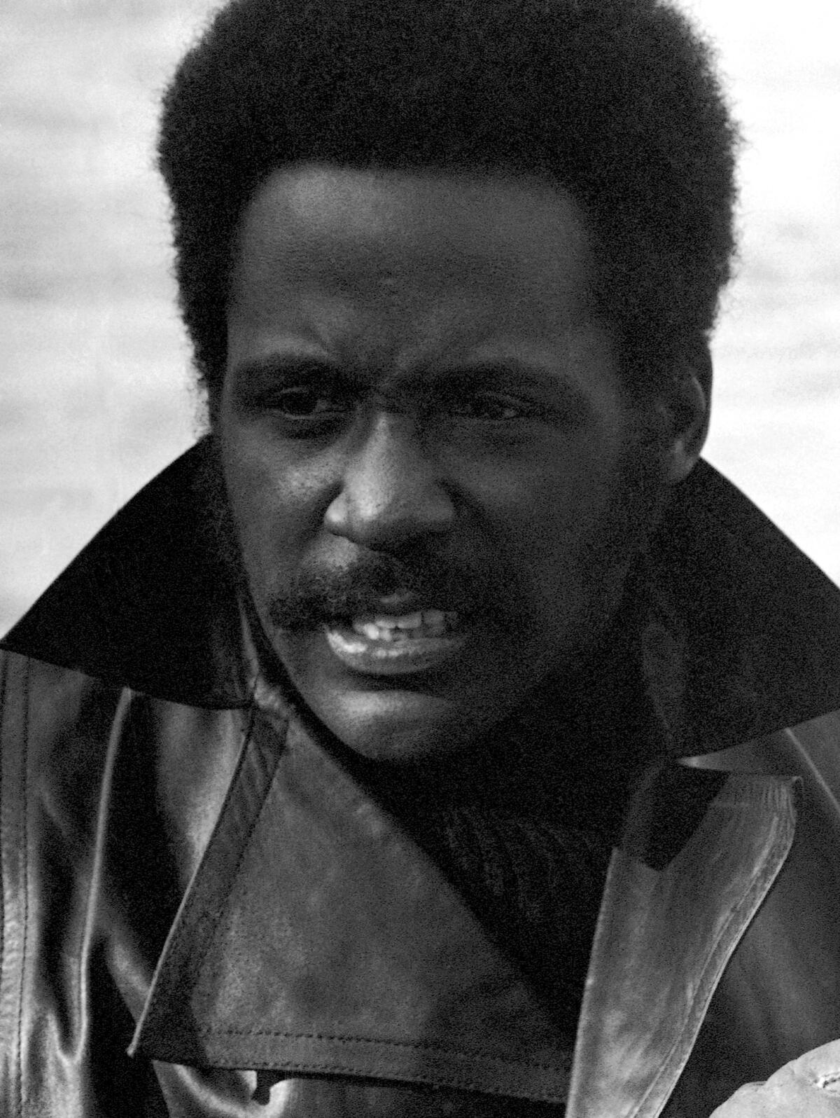 Closeup of a man with a mustache and wearing a black leather jacket.