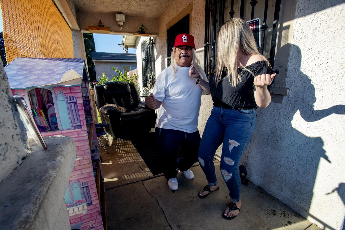 Genaro Rangel usa una peluca y baila con su hija Wendy en el porche de su casa en Santa Ana.