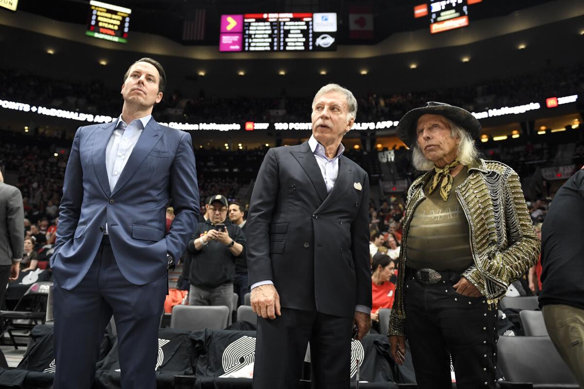 Denver Nuggets president Josh Kroenke stands on the court next to his father, Stan, and NBA fan Jimmy Goldstein