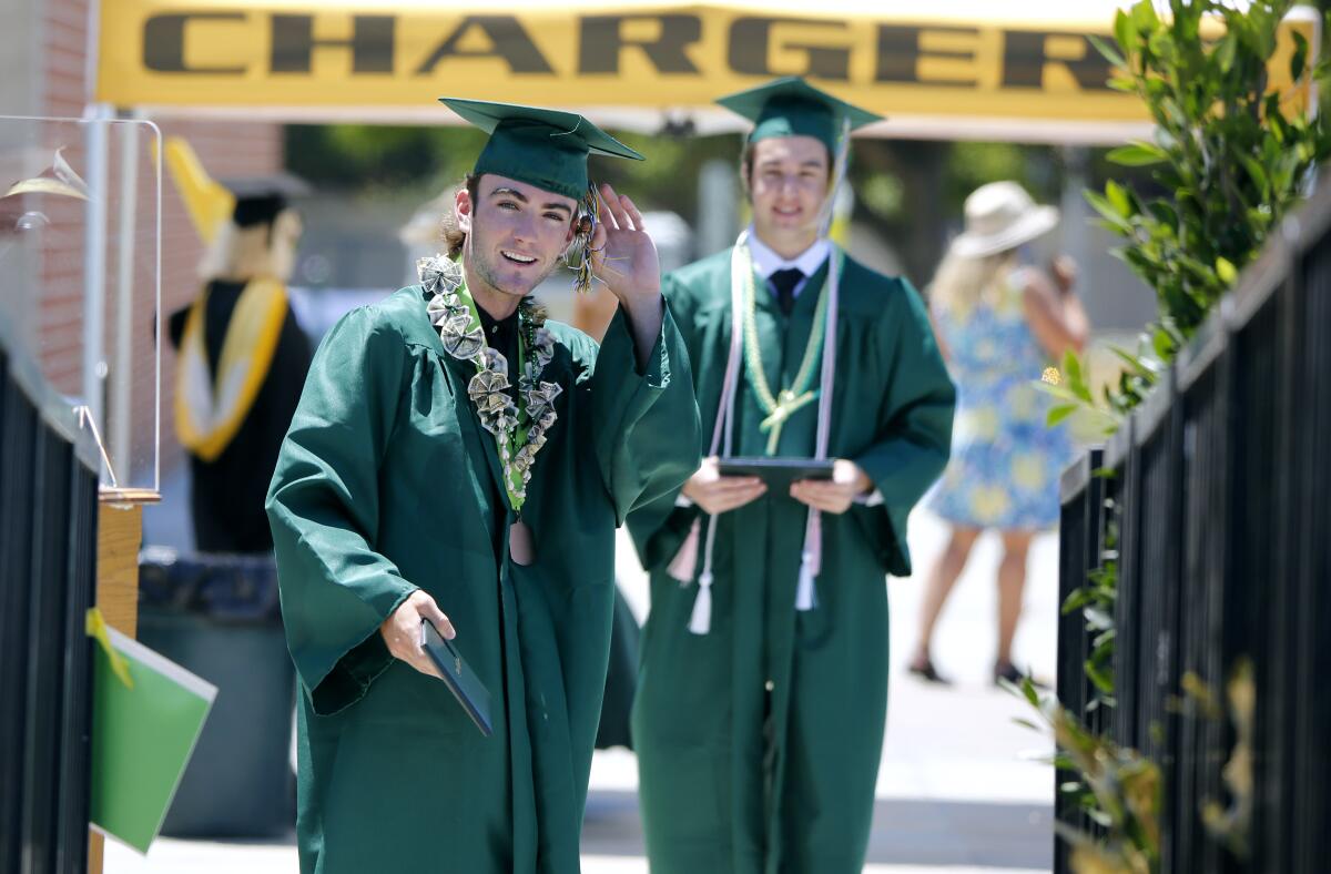 Dylan Delaney, 18 of Huntington Beach, left, fixes his tassel as he waits to have his professional photos taken.