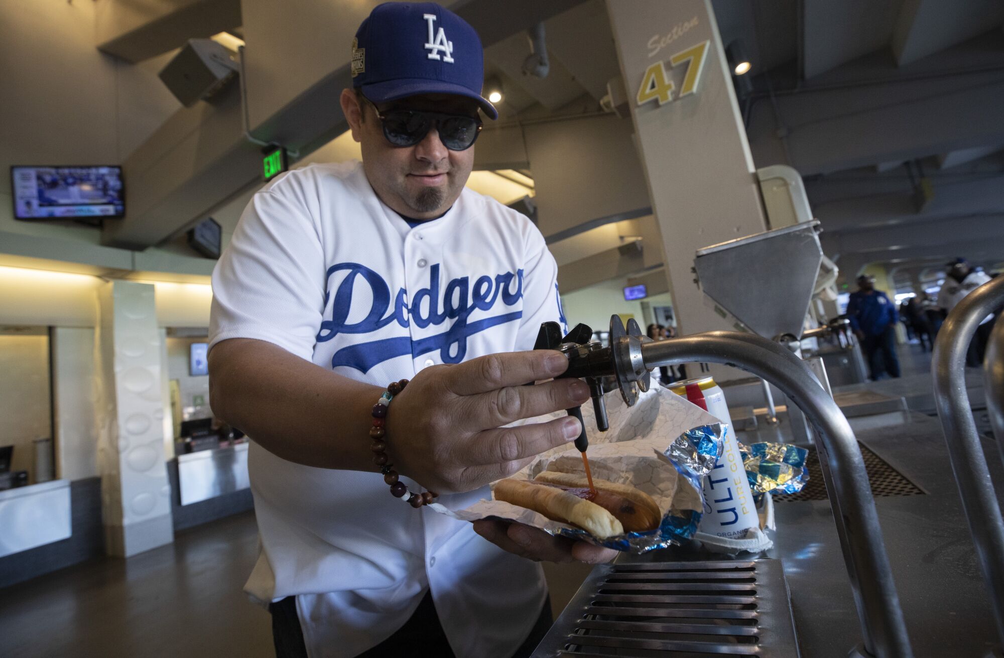 Dodgers fan Carlos Aranibar prepares his Dodger dogs while attending the team's home opener with family.