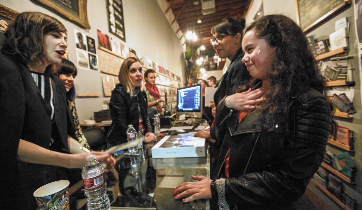 Maude Saenz, 12, interacts with Sleater-Kinney band members Carrie Brownstein, from left, Janet Weiss and Corin Tucker at an in-store signing at Origami Vinyl record shop, in Echo Park in January 2015. Maude's mother, Laura, 30, stands at her side.