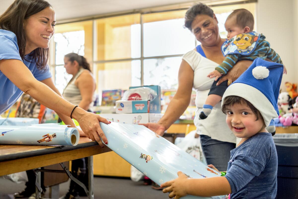 A woman hands a boy a Christmas present