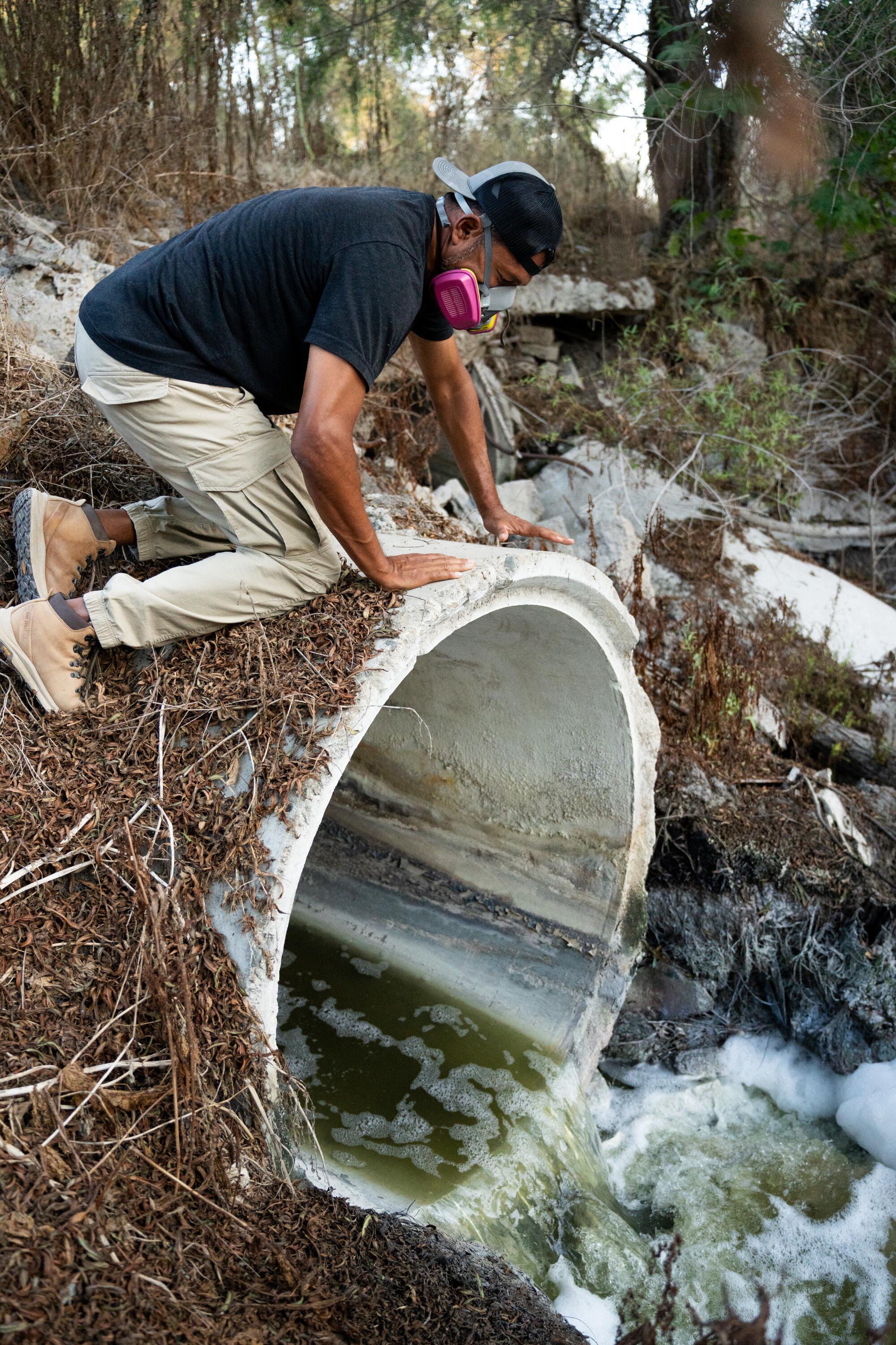 Ramon Chairez crouches above the opening of a large pipe