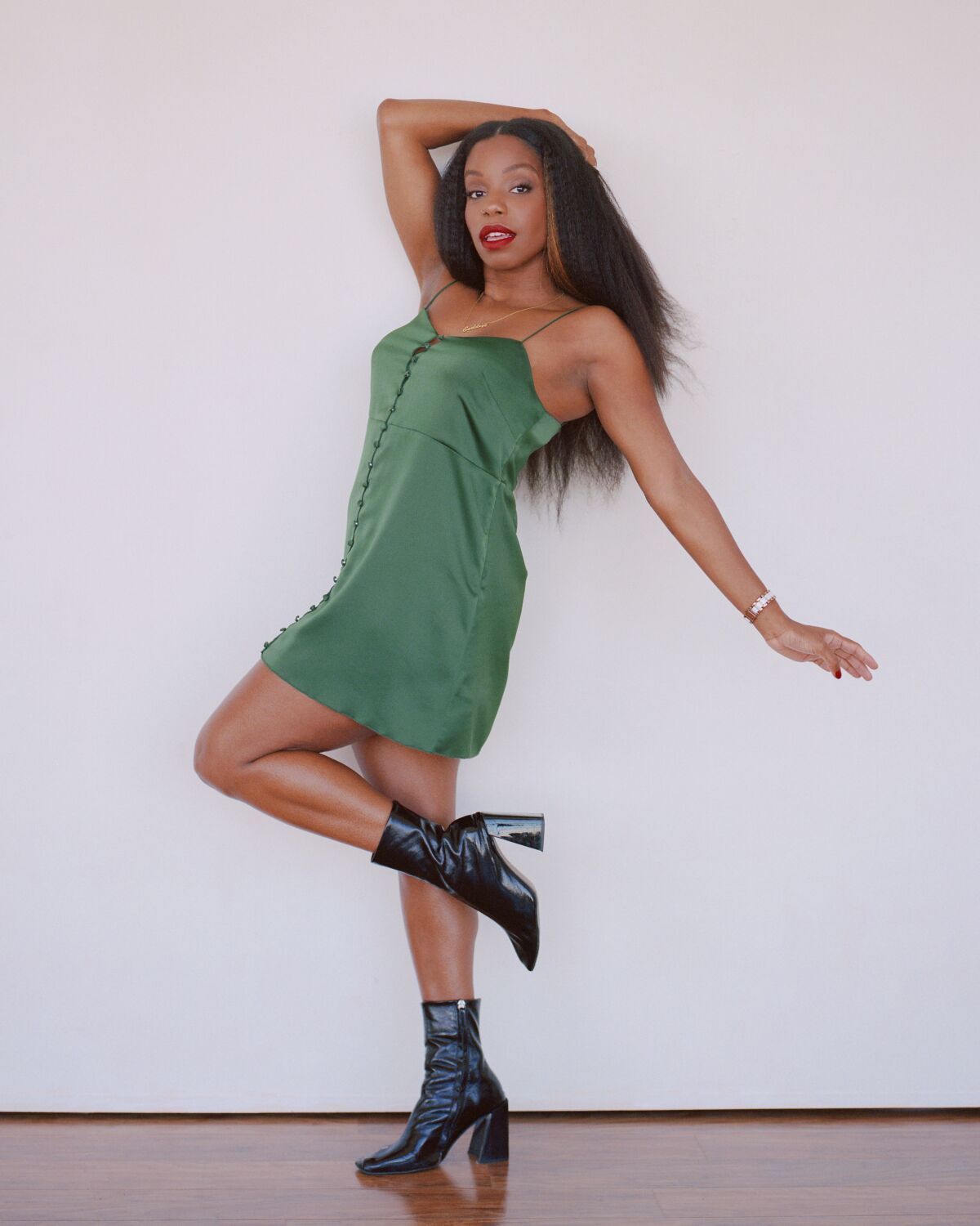 A woman strikes a pose in a green dress and black boots.