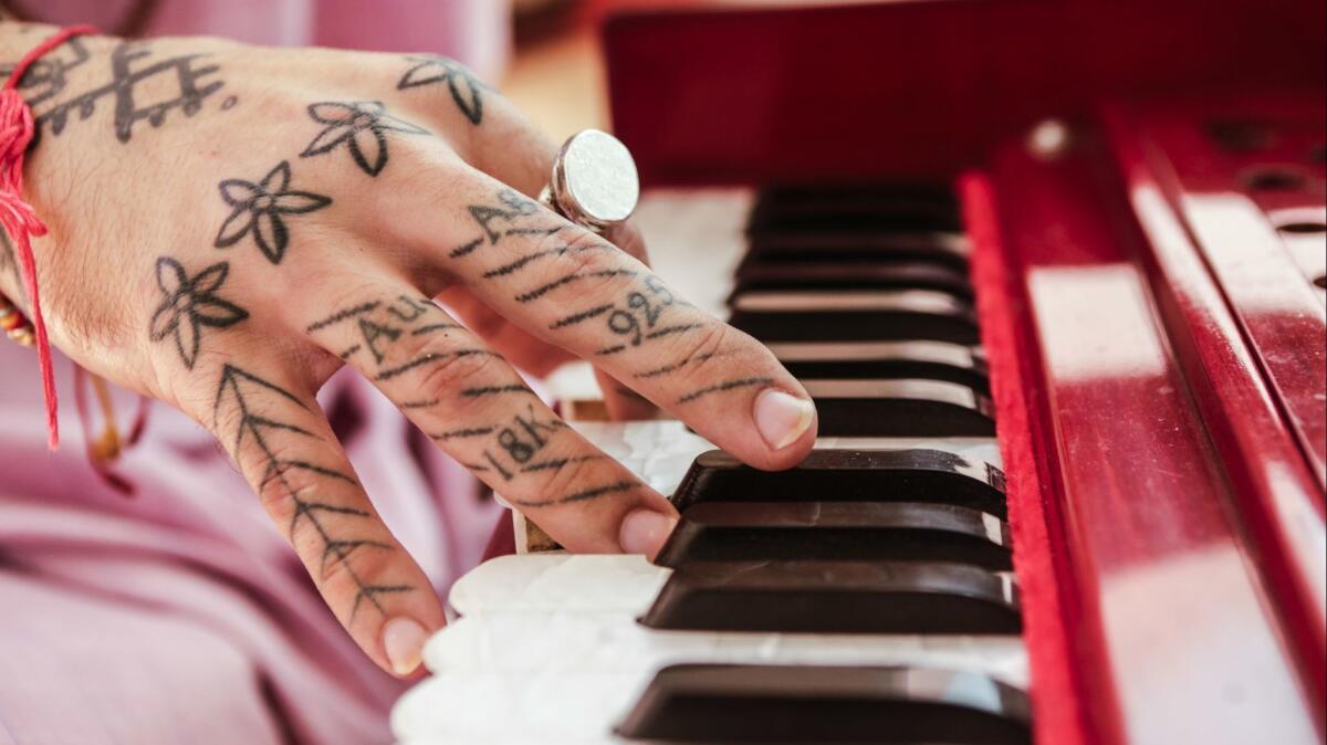 Puja — who is a part-time stick-and-poke tattoo artist, part-time yoga teacher — plays the harmonium, a pump organ.
