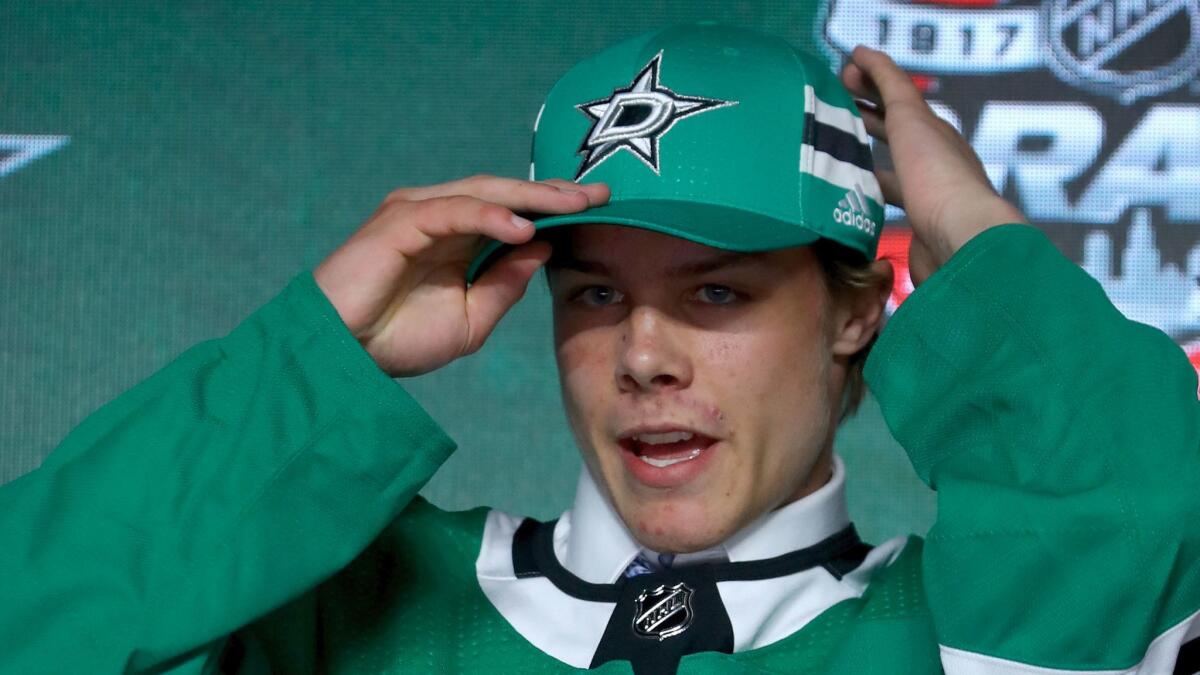 Miro Heiskanen puts on a Dallas Stars hat after being selected third overall during the NHL Draft on June 23.