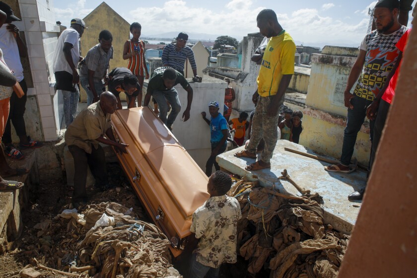 Relatives bury a woman who died in the hospital from her burn injuries caused by a gasoline truck that overturned and exploded, killing dozens in Cap-Haitien Haiti, Wednesday, Dec. 15, 2021. (AP Photo/Odelyn Joseph)