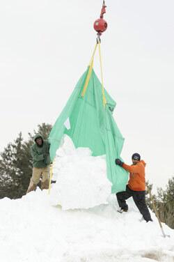 James Williams, left, and Roop Singh unload a tarp full of snow collected from the Highand Park Market in Glastonbury, Conn.