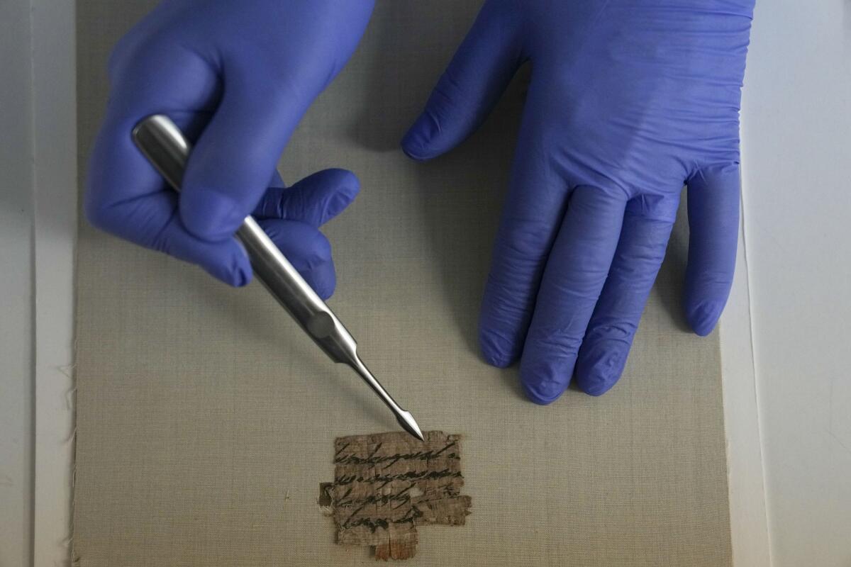 Israeli Antiquities Authority's official conservator, Tanya Bitler, shows a papyrus fragment at their lab inside the Israel Museum in Jerusalem, Wednesday, Sept. 7, 2022. The Israel Antiquities Authority, IAA, said Wednesday that it had obtained the previously unknown ancient papyrus bearing a Hebrew inscription that has been dated to around 2,700 years ago and was long held by a Montana resident. The IAA said it authenticated its age using radiocarbon dating, which corresponded with the age of the text's writing style. (AP Photo/Ariel Schalit)