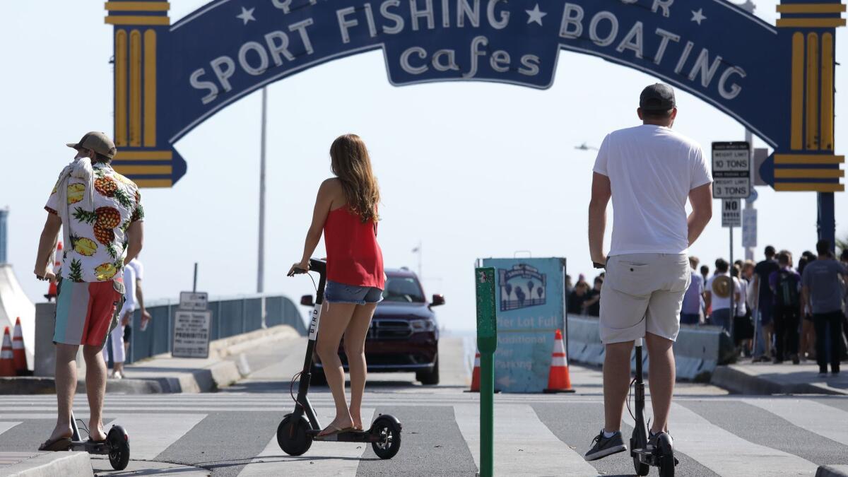 Scooter riders roll past the Santa Monica Pier.