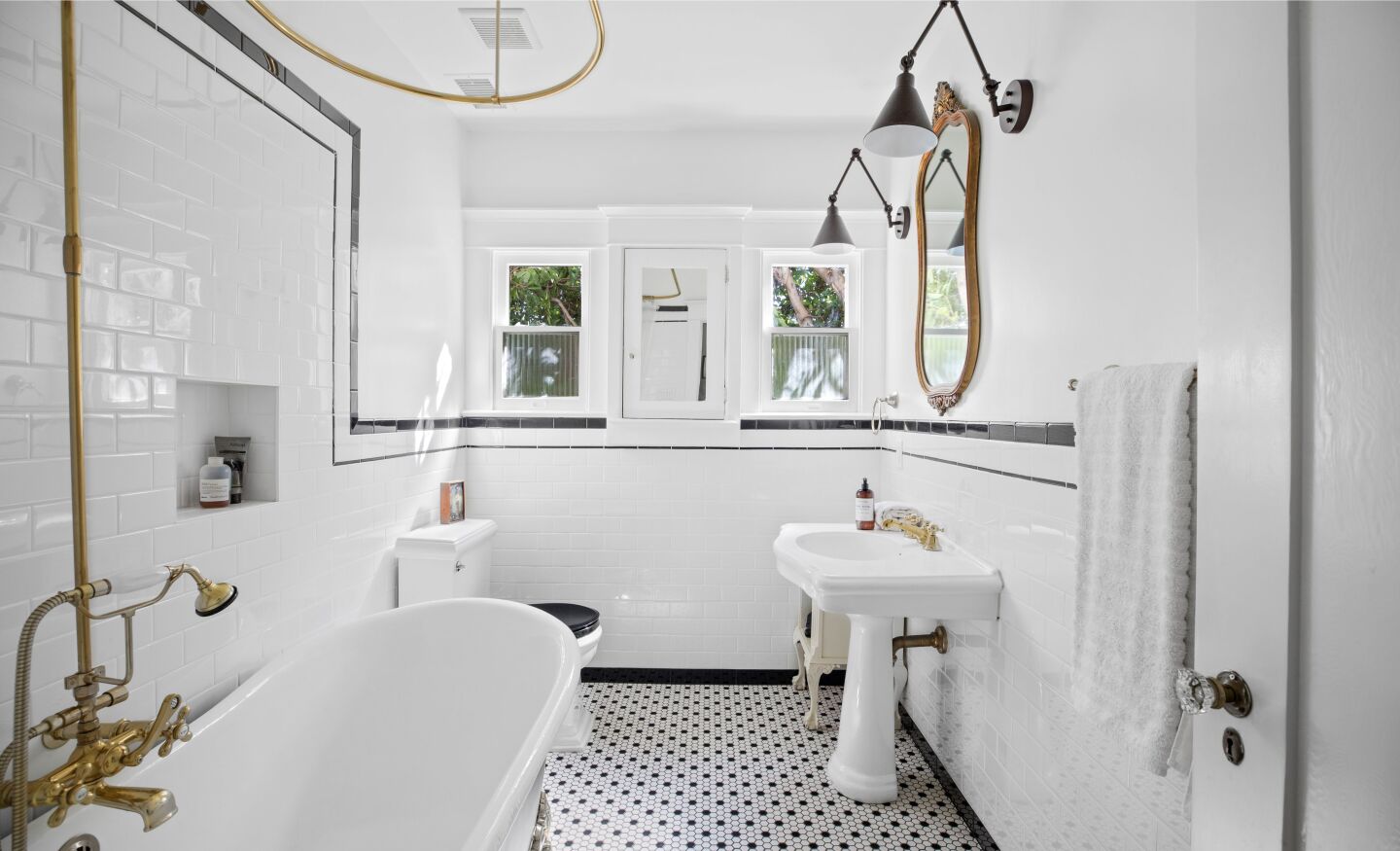 A claw-foot tub and black and white tile in a bathroom.