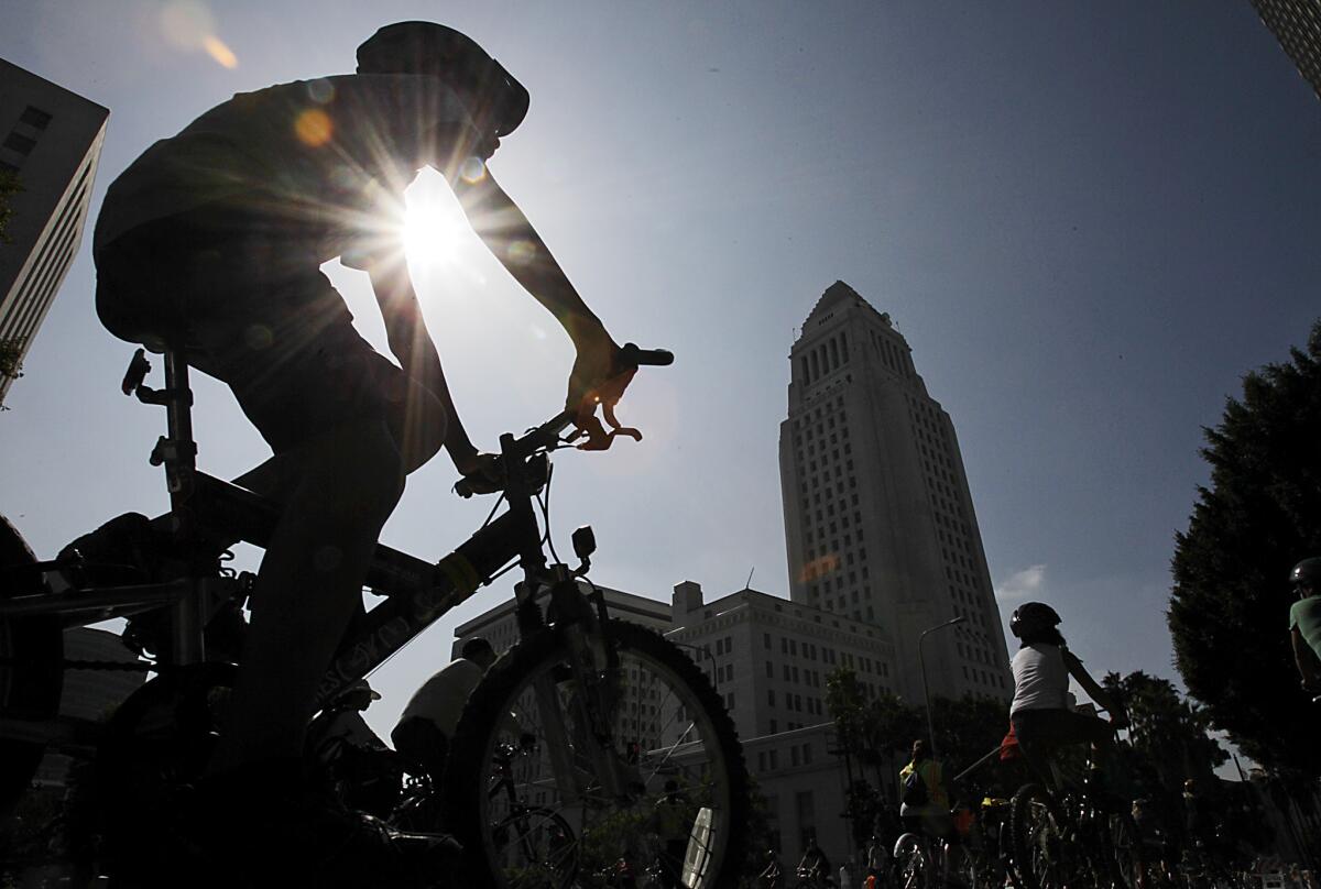 A cyclist wearing a helmet rides past Los Angeles City Hall in 2012.