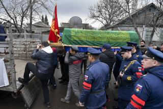 Russian servicemen stand next as people load a coffin with the body of Russian Army soldier Rustam Zarifulin, who was killed fighting in Ukraine, onto a truck after a farewell ceremony in his homeland in Kara-Balta, 60 km (37 miles) west of Bishkek, Kyrgyzstan, Sunday, March 27, 2022. (AP Photo/Vladimir Voronin)