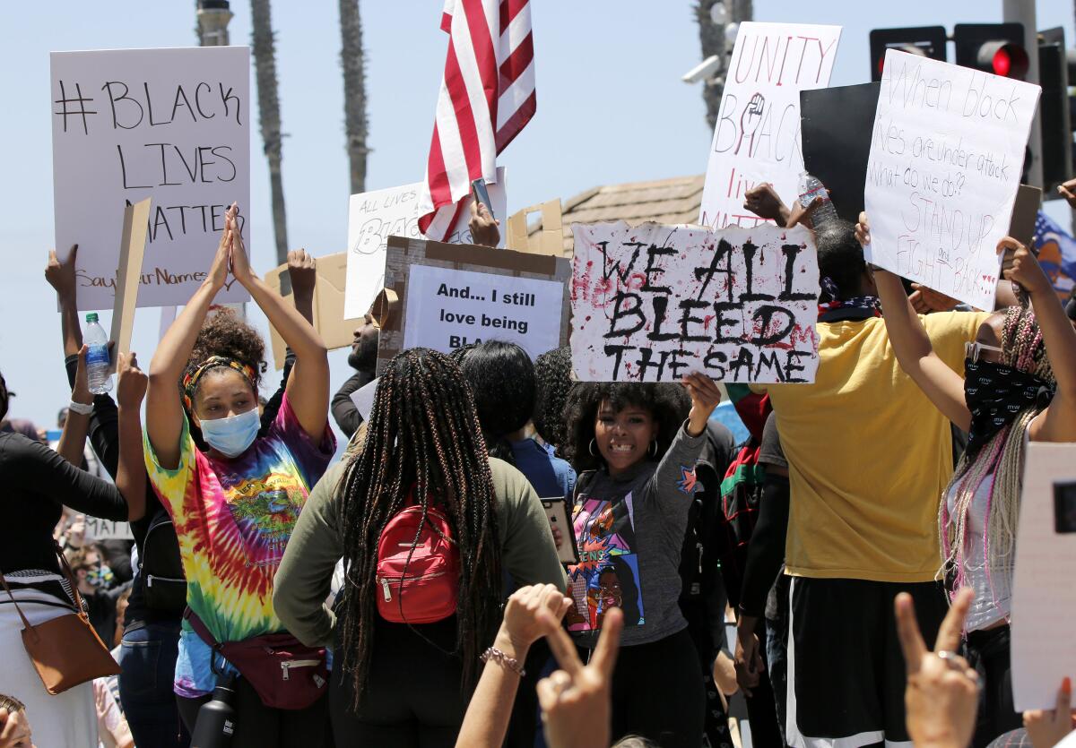 Protesters hold up signs during a Black Lives Matter protest on Main Street and Pacific Coast Highway in Huntington Beach. 