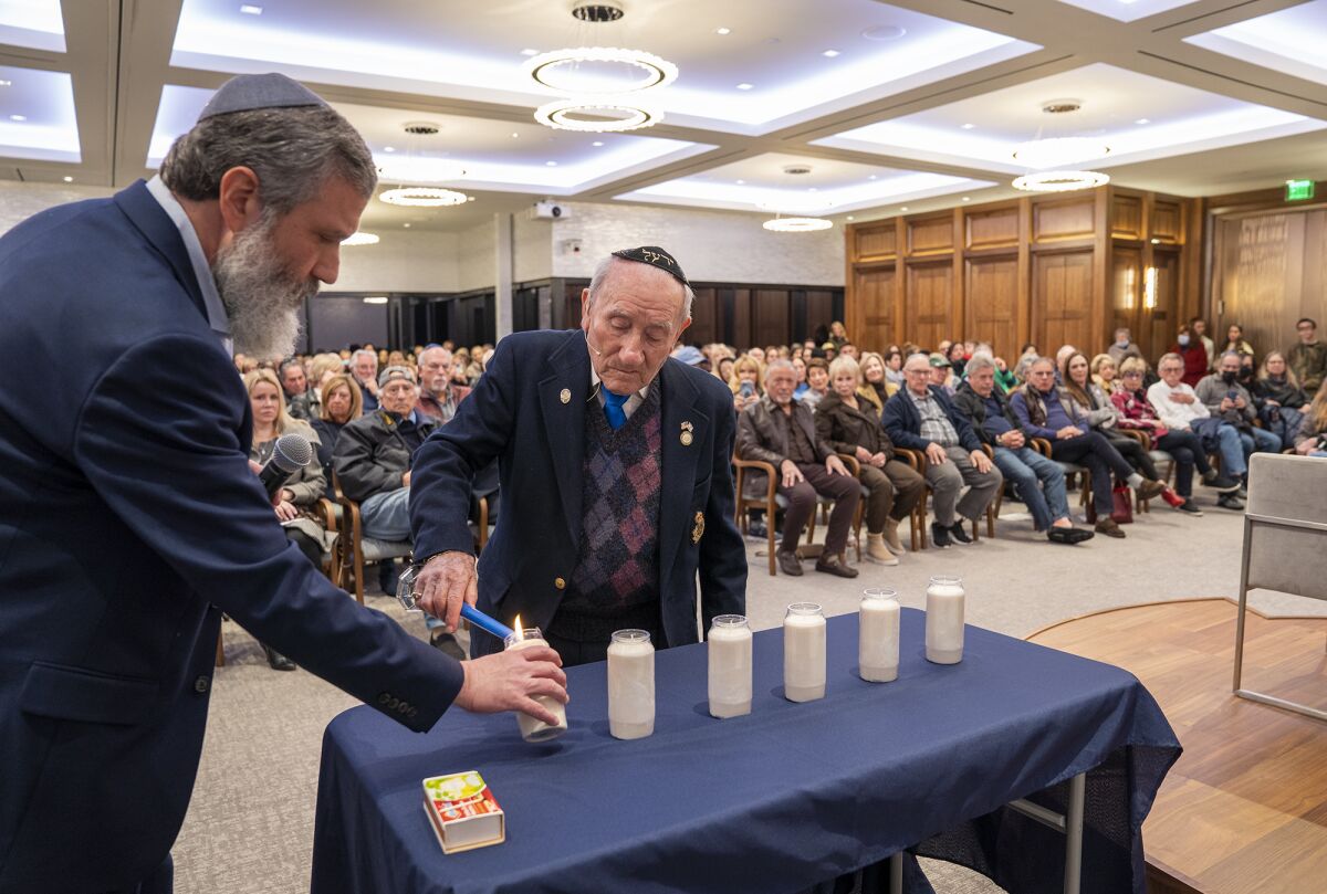 Survivor Joseph Alexander lights a candle in remembrance of those lost in the Holocaust on Sunday in Newport Beach.