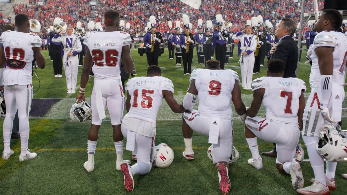 Nebraska's Michael Rose-Ivey (15), DaiShon Neal (9) and Mohamed Barry (7) kneel during the national anthem Sept. 24 at Ryan Field.