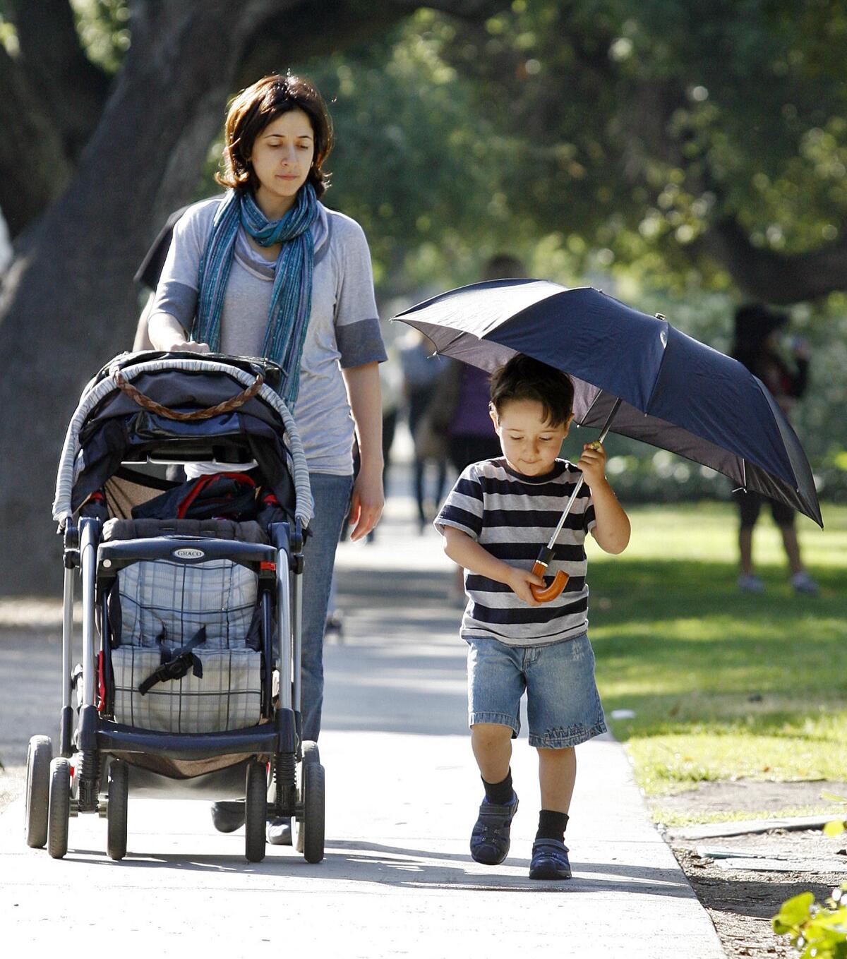 File Photo: Edgar Galstyan, then 3, holds an umbrella, partly to keep from the sun, but more for play, as he walks home with his mom Lusine Tsaturyan after making the morning drop off of a sibling at R.D. White Elementary School in Glendale on May 9, 2012.
