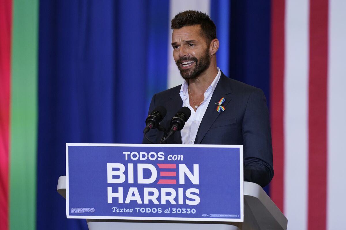 Pop star Ricky Martin speaks at a Biden event in Kissimmee, Fla., with a Spanish-language sign, "Todos con Biden-Harris."