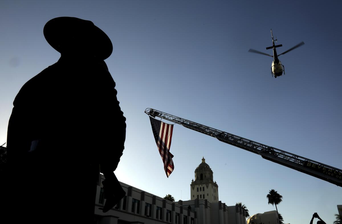  A member of the Beverly Hills Police Honor Guard watches as a L.A P.D. helicopter does a flyover 
