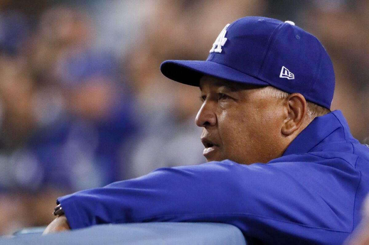 Dodgers manager Dave Roberts watches from the dugout during a game.