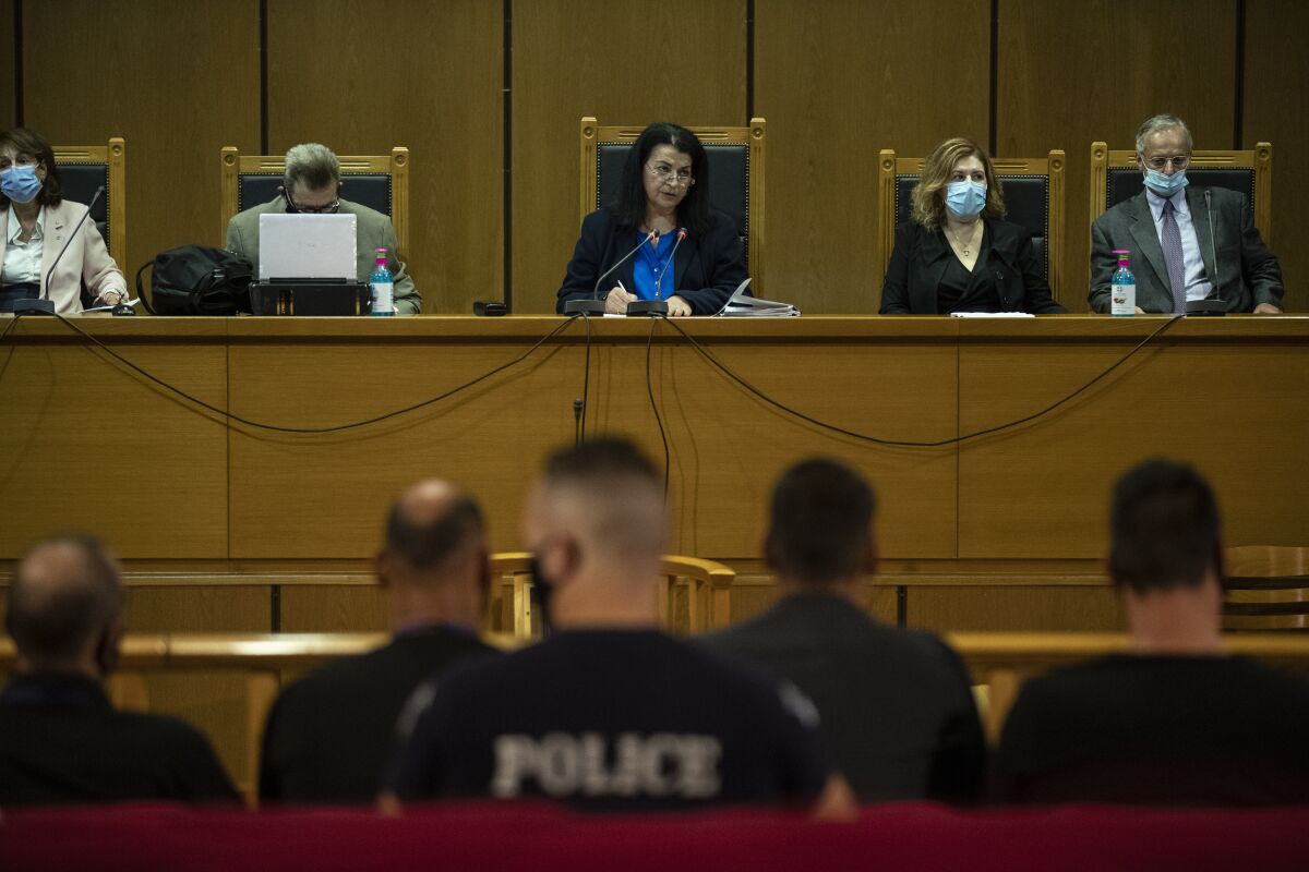 Judge Maria Lepenioti, center, delivers the verdict in a court in Athens, Wednesday, Oct. 7, 2020. The court has ruled the far-right Golden Dawn party was operating as a criminal organization, delivering landmark guilty verdicts in a politically charged five-year trial against dozens of defendants, including former lawmakers of what had become Greece's third largest party. (AP Photo/Petros Giannakouris)