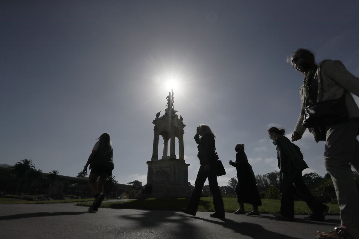 Visitors to Golden Gate Park in San Francisco wear protective masks on a sunny day.