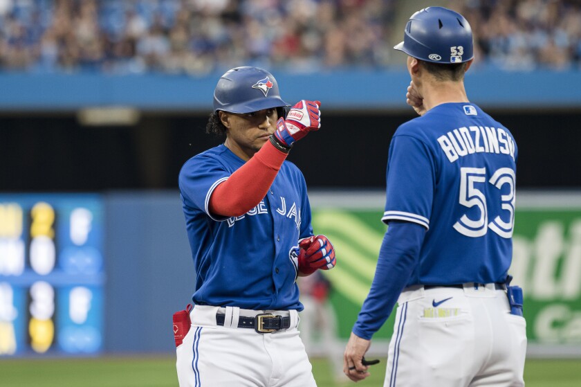 Toronto Blue Jays' Santiago Espinal (5) celebrates with first base coach Mark Budzinski after hitting a single against the Boston Red Sox during the second inning of a baseball game Wednesday, June 29, 2022, in Toronto. (Christopher Katsarov/The Canadian Press via AP)