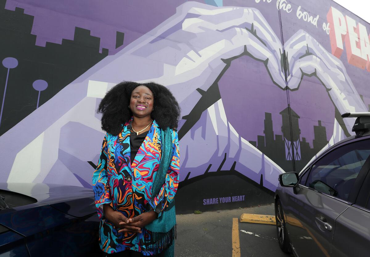 Dr. Bernice Rumala stands in front of the Purple Unity Project mural, her favorite, in Santa Ana.