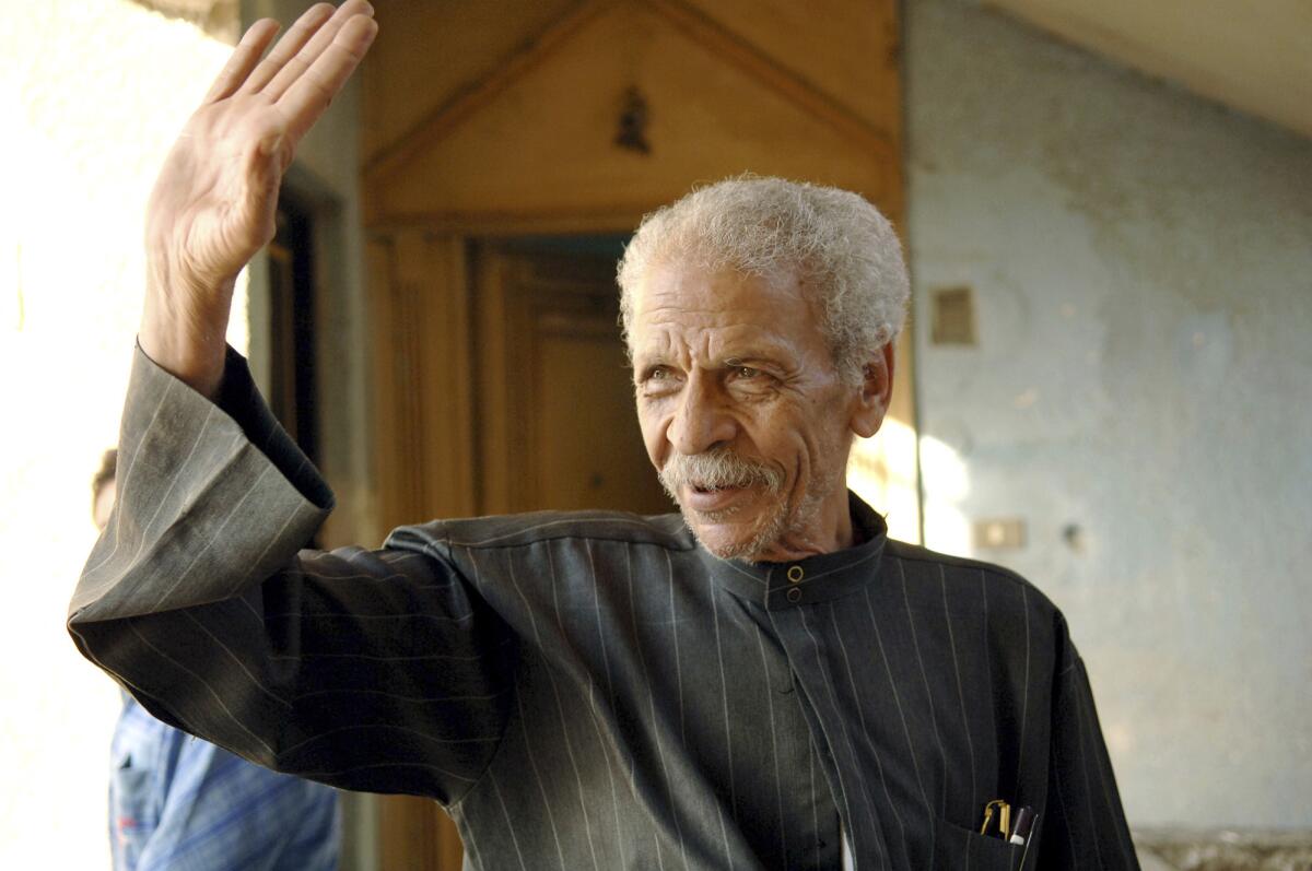 Egyptian poet Ahmed Fouad Negm returns the greetings of a neighbor outside his home in Cairo in 2006.