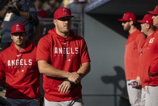 Los Angeles Angels' Mike Trout walks in the dugout before a baseball game.