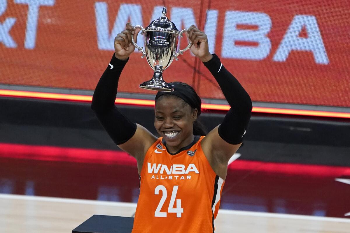 Team WNBA's Arike Ogunbowale holds up the MVP trophy after Team WNBA defeated Team USA.