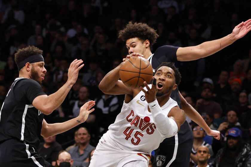 Cleveland Cavaliers guard Donovan Mitchell (45) drives to the basket against Brooklyn Nets guard Seth Curry, left, and forward Cameron Johnson (2) during the first half of an NBA basketball game, Tuesday, March 21, 2023, in New York. (AP Photo/Noah K. Murray)