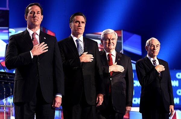 Republican presidential candidates, from left, former U.S. Sen. Rick Santorum, former Speaker of the House Newt Gingrich, former Massachusetts Gov. Mitt Romney and U.S. Rep. Ron Paul of Texas place their hands over their hearts as the national anthem is played before the start of the debate at the North Charleston Coliseum.